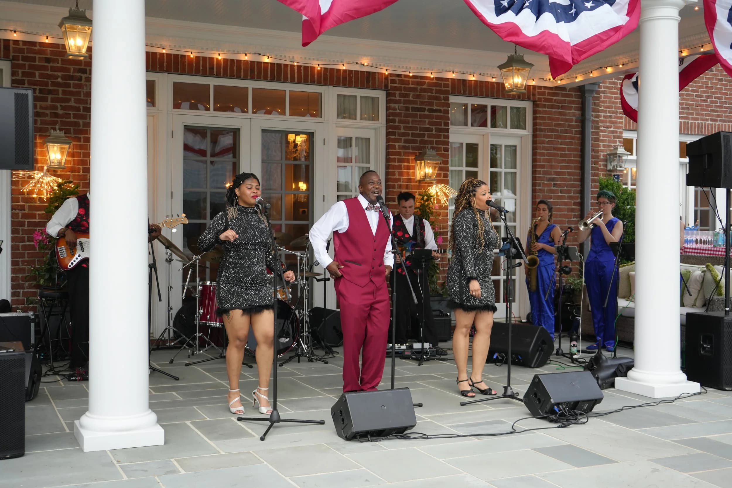 The band's vocalists performing on a string-lit patio stage