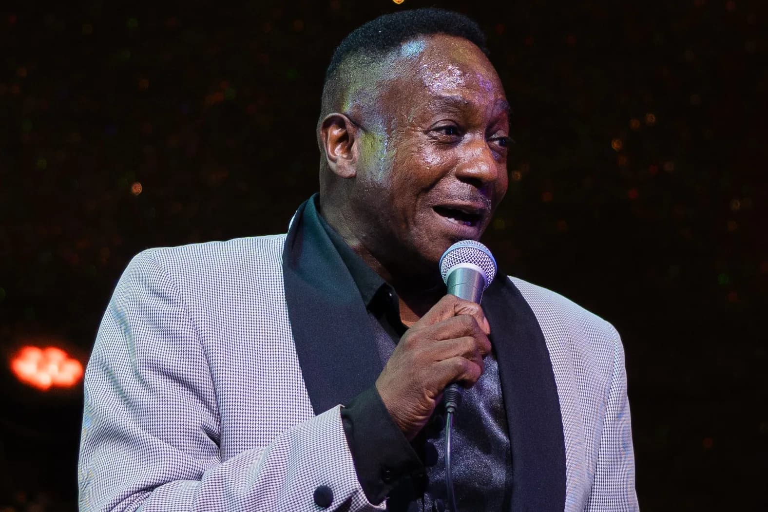 A lead vocalist smiling mid-song