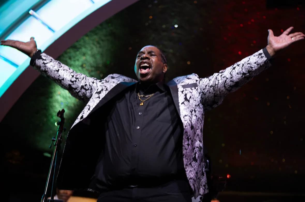 A vocalist throwing his arms wide mid-song