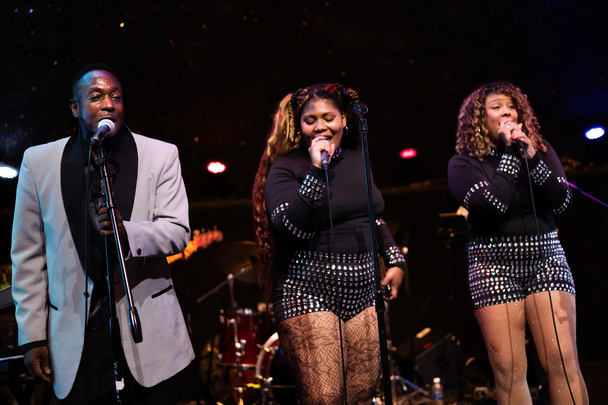 Three of Spotlite's vocalists singing under stage lights